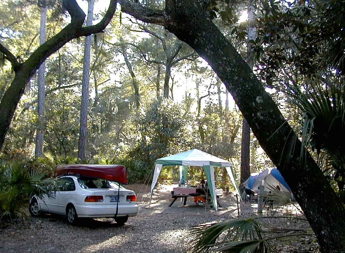A car parked at a campsite with camping gear unloaded
